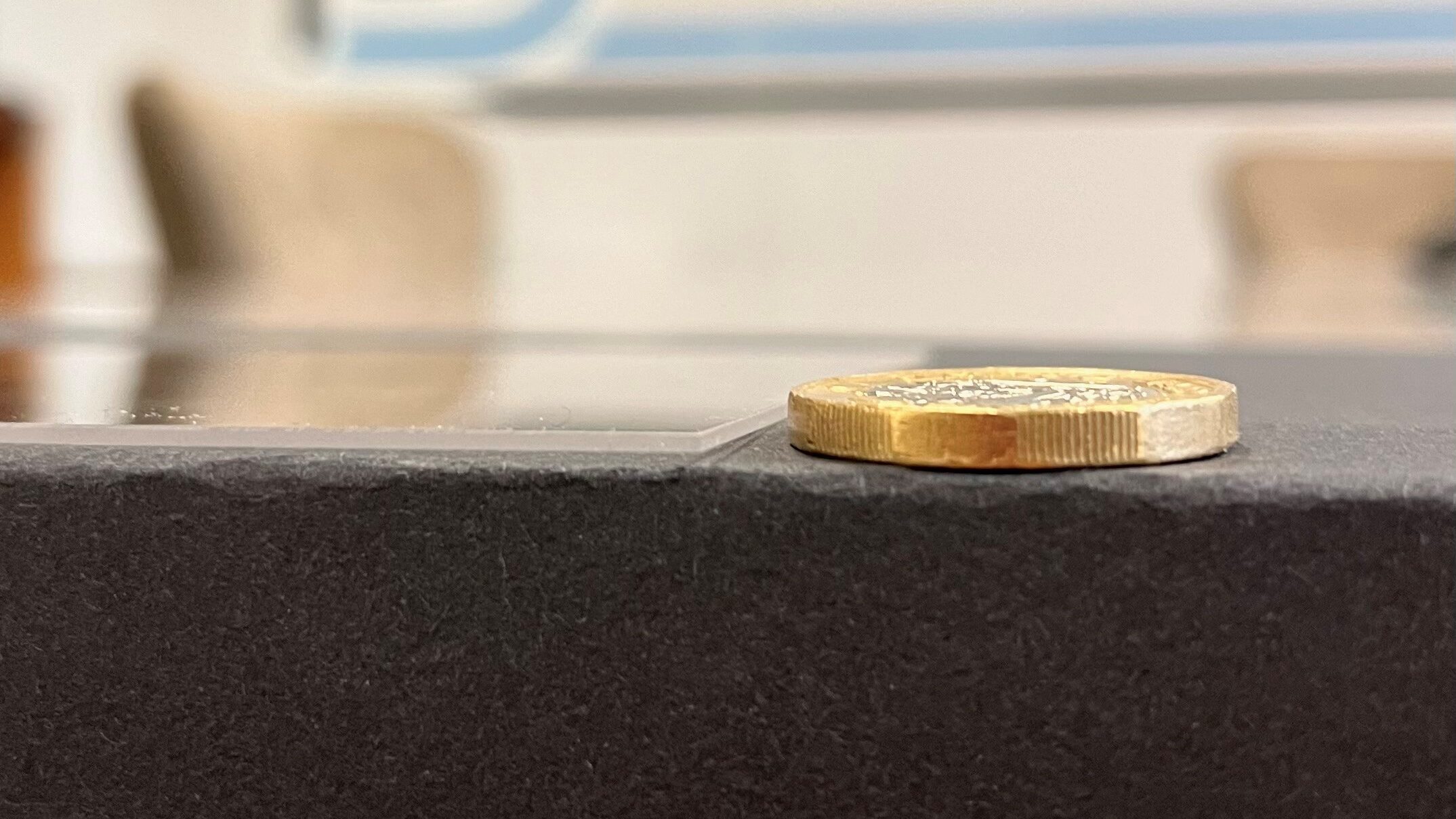 A £1 coin laying next a 0.5mm thickness cast acrylic panel